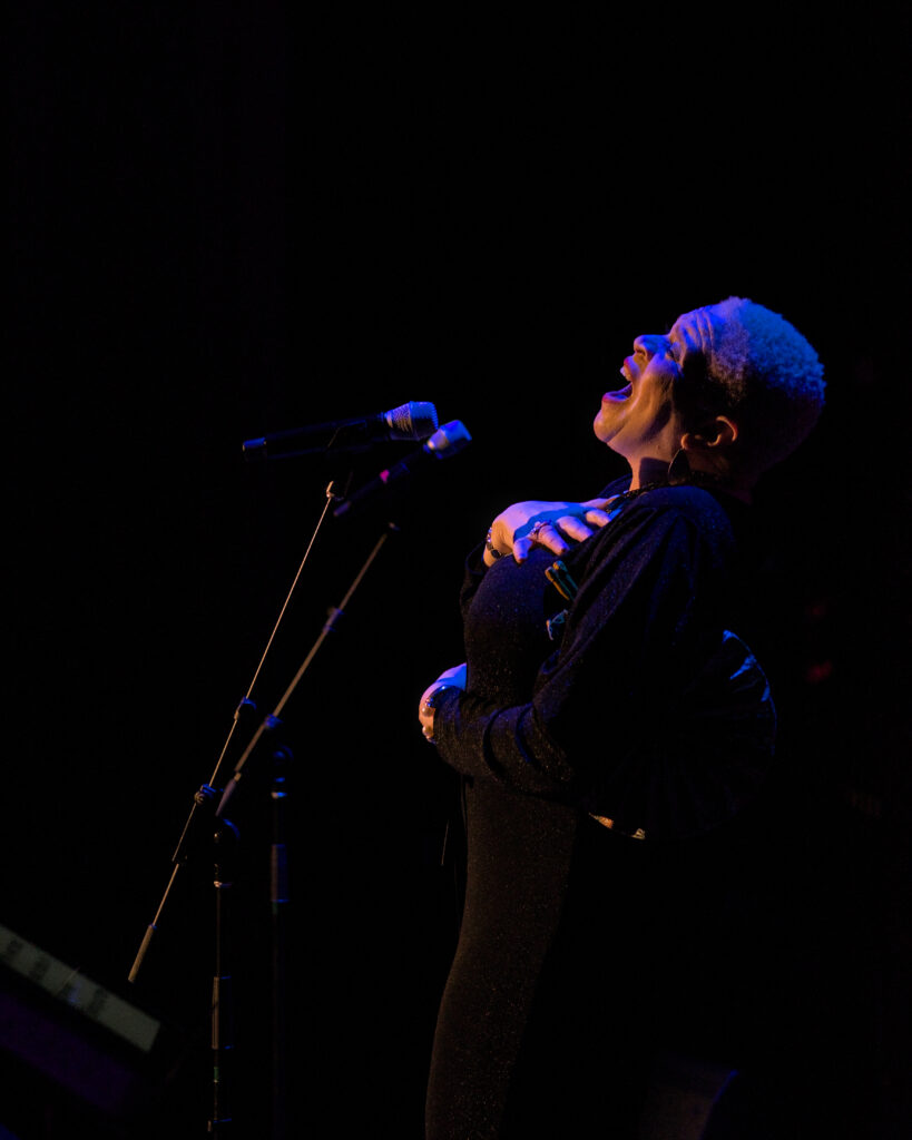 LaRhonda Steele performing live soul, blues, and jazz music on stage at the historic Columbia Theatre in Longview, Washington, during the venue’s centennial celebration with band and community choir.
