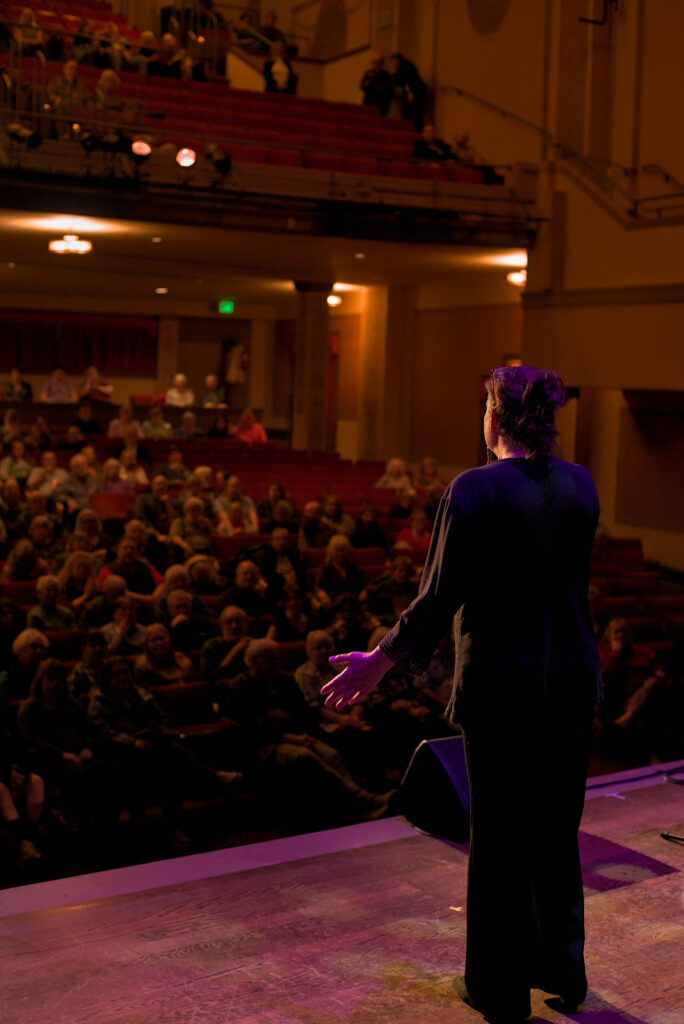 LaRhonda Steele performing live soul, blues, and jazz music on stage at the historic Columbia Theatre in Longview, Washington, during the venue’s centennial celebration with band and community choir.